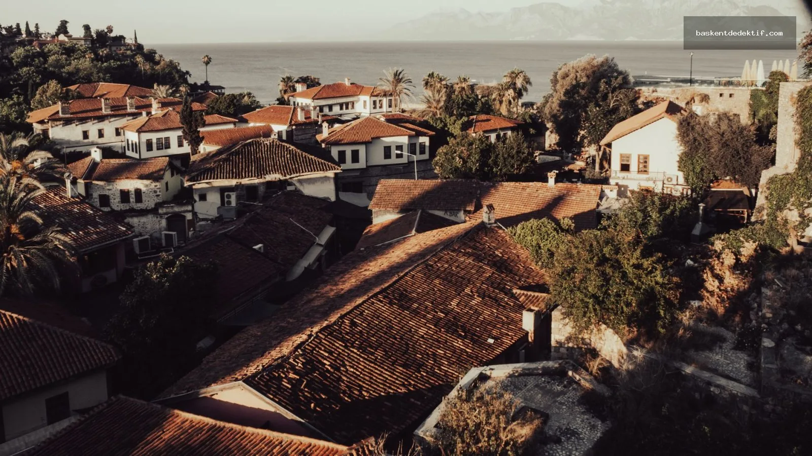 Antalya Kepez’te sakin bir deniz manzarası ve kırmızı çatıların yanında yeşil bir