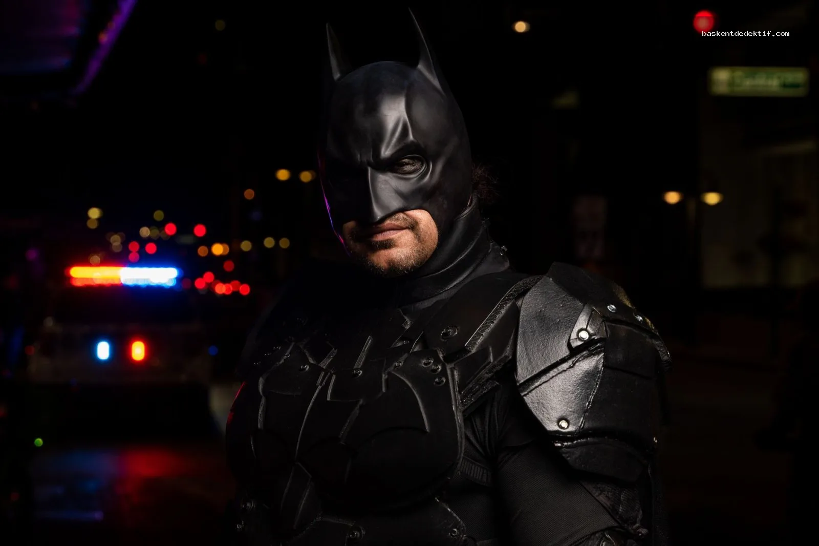 Gece atmosferinde polis ışıkları altında detaylı kostümlü Dedektif Batman