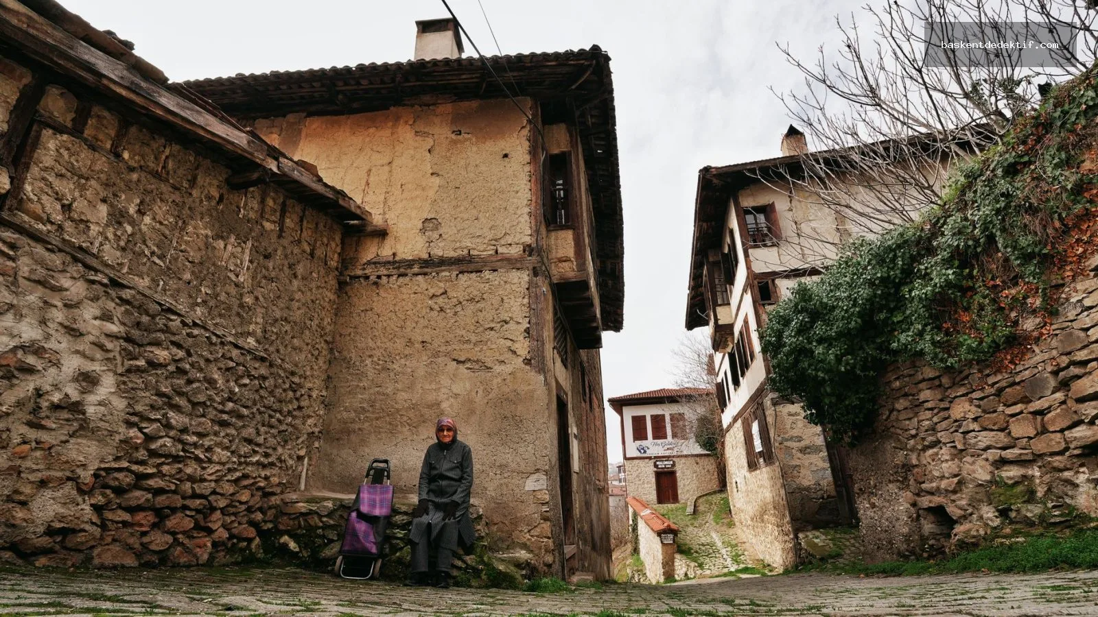 Safranbolu'daki tarihi sokaklarda oturan yaşlı kadın ve Osmanlı döneminin dedektif kıyafeti